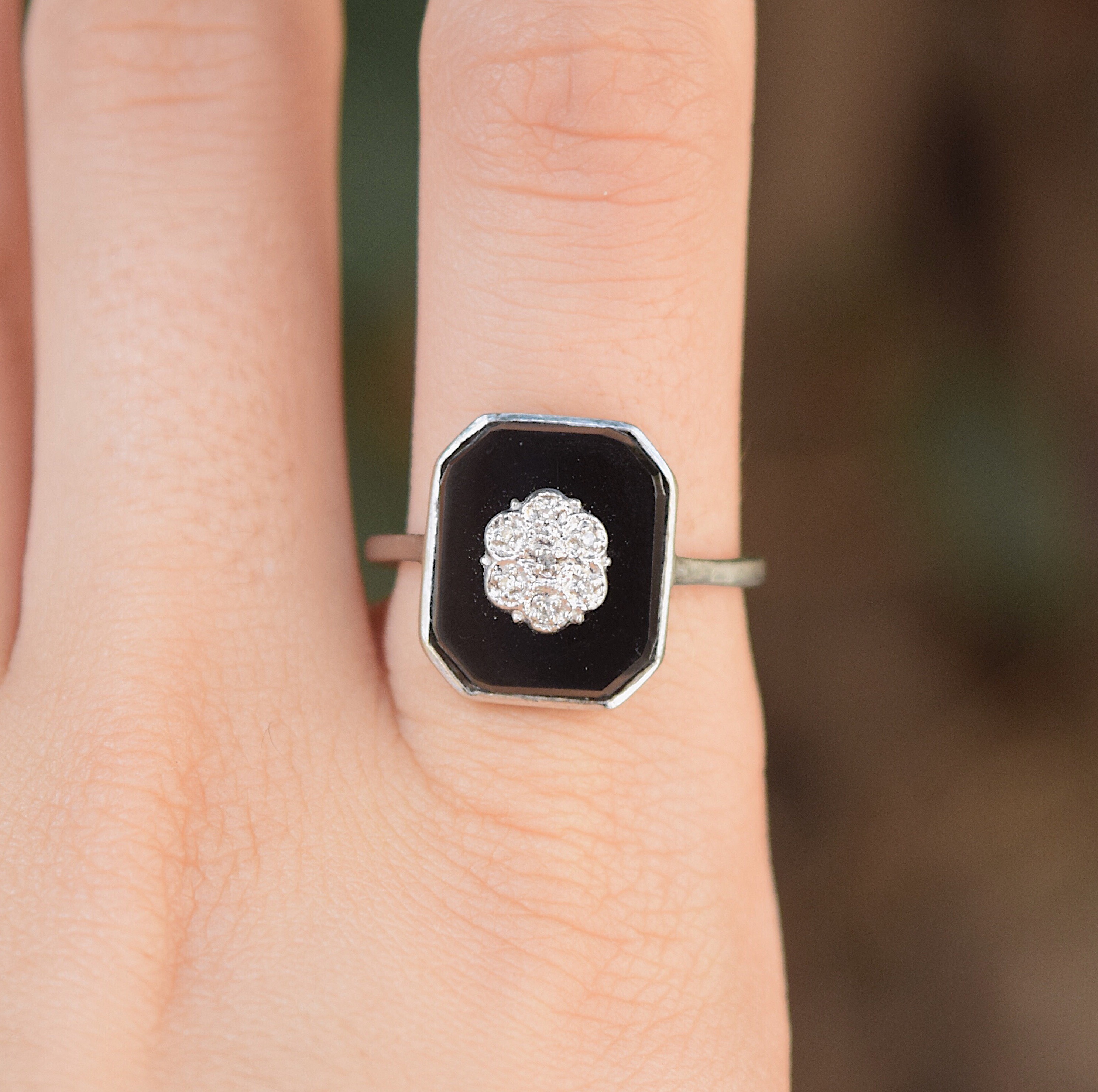 טבעת זהב עם אוניקס ועליו פרח משובץ ביהלומים קטנים.